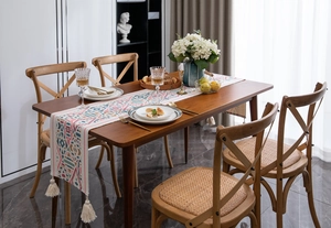 Runner da tavola boho con motivi geometrici colorati e nappe su un tavolo in legno