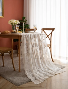 Détail d'une nappe en dentelle blanche avec broderie florale et bord festonné
