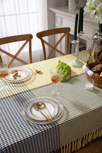 Detail of modern houndstooth and yellow tablecloth with elegant fringe tassels and texture