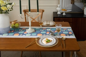 Détail du chemin de table bleu avec motifs de poissons et glands sur table en bois