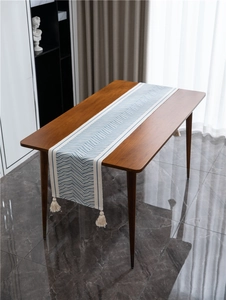 Close-up of blue and white geometric wave pattern table runner with cotton tassels
