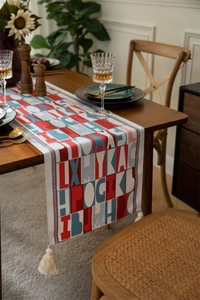 Detailed macro view of woven table runner featuring red geometric letters and cotton tassels