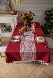 Detalle del mantel de jacquard rojo con diseño floral blanco y borlas de flecos