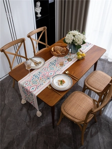 Dettaglio runner da tavola bohémien con motivi geometrici colorati e nappe di cotone