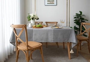 Close-up of modern grey striped tablecloth fabric featuring elegant tassels and woven texture