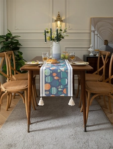 Détail d'un chemin de table bleu moderne à imprimé poissons avec d'élégants pompons blancs