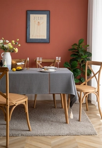 Detail of grey houndstooth tablecloth with white fringe tassels on a wooden table