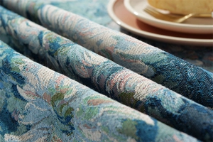 Close-up of vintage blue daisy jacquard tablecloth fabric with fringe and floral pattern