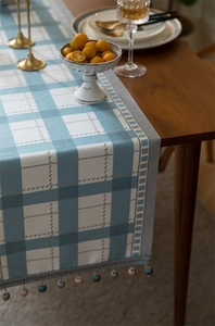 Close-up of geometric blue plaid table runner with decorative beaded fringe and tassels