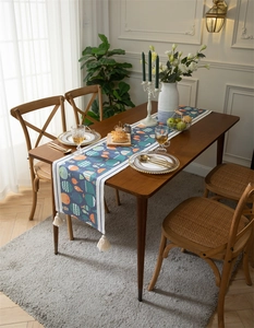 Détail d'un chemin de table bleu à motifs de poissons et glands en coton blanc
