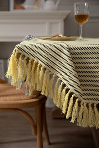 Detailed close-up of yellow and black twill woven tablecloth with elegant fringe tassels