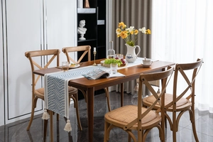Close-up of geometric wave patterns and cream cotton tassels on a modern table runner