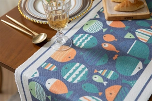 Détail d'un chemin de table bleu en coton avec motifs poissons et bordures à franges