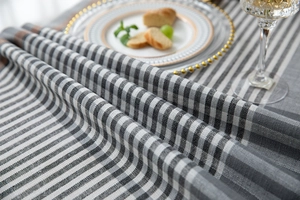 Macro detail of geometric jacquard stripes and tassels on gray and white table runner