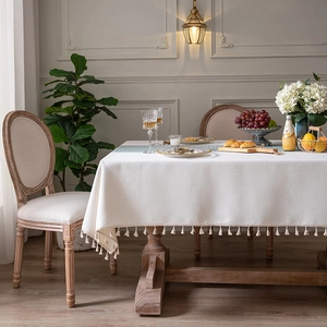 Houndstooth textured tablecloth with fringe tassels on a vintage wooden dining table