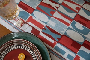 Detailed view of jacquard table runner with red and blue letters on dark wood table