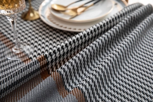 Detail of woven houndstooth and striped tablecloth with fringe texture in a dining setting