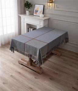 Detail of modern houndstooth and striped tablecloth with elegant woven tassel edges