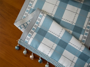 Detail of blue and white checkered table runner with hanging ball tassel fringe