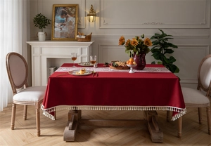 Detalle del mantel de jacquard rojo con flecos de pompones y camino de mesa de encaje