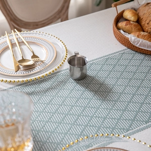 Green and white geometric jacquard tablecloth with tassel fringe in a modern dining setting