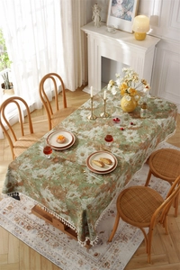 Detail of vintage oil painting style floral tablecloth with white fringe and woven texture