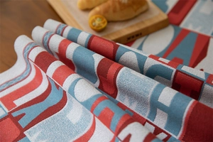 Close-up of jacquard table runner with red and blue letters and fringe detail