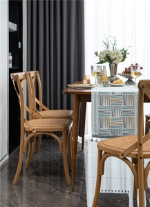 Close-up of geometric pattern table runner on wooden dining table with cross back chairs