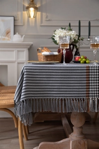 Detail of houndstooth tablecloth featuring long gray tassels and orange stripe accents