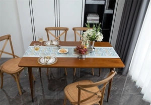 Detail of chenille table runner with blue and yellow geometric patterns on wood table