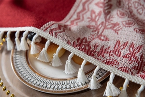 Detalle del camino de mesa navideño de jacquard rojo y beige con renos y flecos blancos