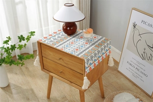 Detail of bohemian geometric dust cover with cream tassels on a wooden bedside table