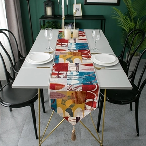 Detail of red jacquard table runner featuring geometric patterns and hanging tassels
