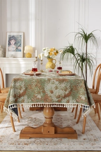 Close-up of vintage jacquard tablecloth with orange floral patterns and cream fringe edge
