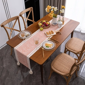 Ethnic geometric wave pattern cotton table runner with tassels on a dark wooden dining table