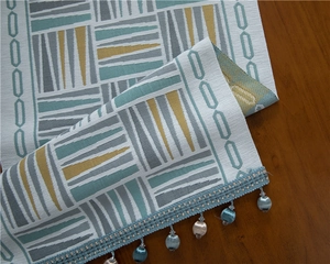 Detail of chenille table runner featuring colorful geometric patterns and beaded tassels