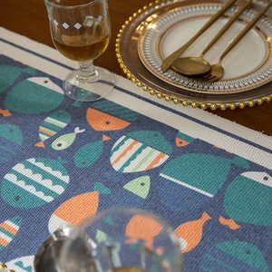 Chemin de table moderne bleu à motifs de poissons et pompons sur une table en bois