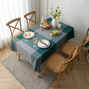 Modern dark green geometric plaid tablecloth with white fringe on a rectangular dining table