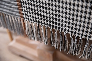 Macro shot of houndstooth tablecloth texture with fringe edges and geometric color blocks