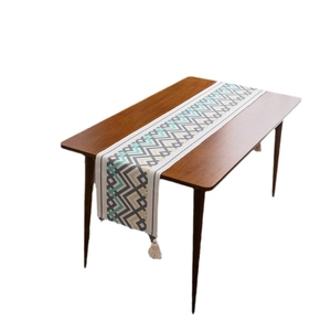 Runner da tavola boho con motivo a zigzag e nappe su tavolo in legno scuro