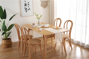 Close-up of wooden dining set featuring a minimalist table and chairs with woven seats