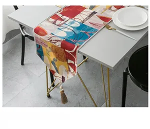 Detail of red jacquard table runner with decorative tassels and geometric pattern