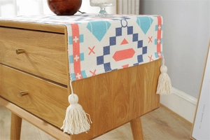 Macro detail of geometric woven fabric cover with fringe tassels on a wooden cabinet
