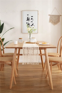 Detail of cream crochet lace table runner with intricate fringe on wooden dining table