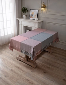 Detail of pink and grey houndstooth tablecloth with fringed edges in modern room
