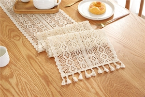 Detail of crochet lace table runner with geometric cutouts and elegant tassel fringe edge