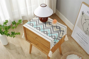 Detail of geometric pattern dust cover with tassels on a wooden bedside table