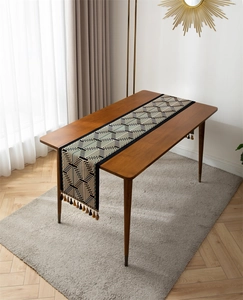 Detail of blue and beige jacquard table runner with geometric patterns and fringe