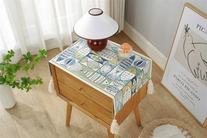 Close-up of abstract fish pattern and cream woven tassels on a cotton linen runner