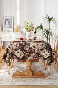 Detailed view of vintage jacquard tablecloth featuring floral patterns and cream tassels